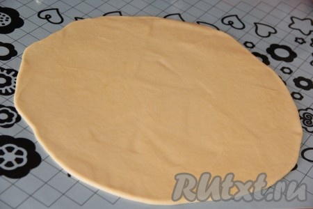 Готовое тесто выложить на силиконовый коврик или стол, присыпанный мукой, и раскатать с помощью скалки в круг. Диаметр круга примерно 30 см.
