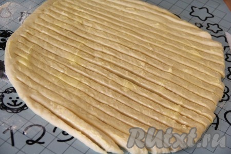 Затем разрезать тесто на полоски шириной примерно 1 см, не дорезая полоски с одного края до конца.