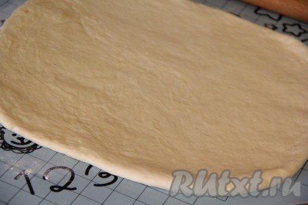 Готовое тесто выложить на силиконовый коврик или присыпанный мукой стол и хорошо обмять. Раскатать тесто скалкой в прямоугольный пласт (не тонко).