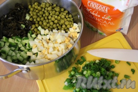 Лук мелко нарезать. С капусты и горошка слить лишнюю жидкость. Соединить морскую капусту, измельченные яйца и огурцы, добавить в салат горошек. 