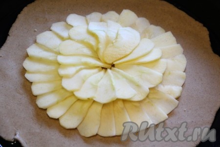 Форму для выпекания смазать растительным маслом, переложить корж на противень. Выложить кусочки яблок на тесто, оставив свободным край теста.