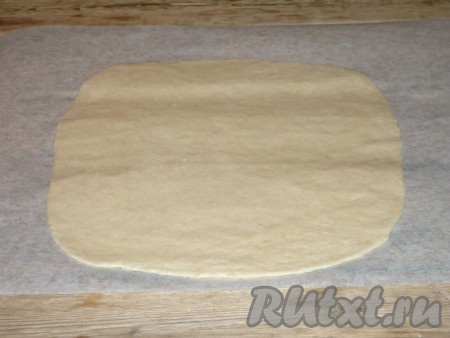 Готовое тесто обмять и разделить на две части (мы будем формировать 2 закрытых пиццы). Вначале на присыпанной мукой поверхности одну часть теста раскатать в достаточно тонкий овал. 