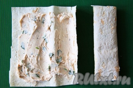 Разрежьте лаваш на прямоугольники и смажьте творожным сыром с зеленью. Сверните лаваш конвертиком в два сложения. 
