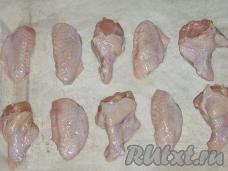 Когда куриные крылья немного замаринуются, выложить их на противень, застеленный пергаментом, и отправить в духовку, разогретую до 180 градусов, на 15 минут. 
