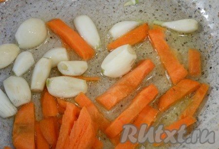 Разогреть в сковороде растительное масле, выложить морковь с чесноком и, быстро перемешивая, обжарить овощи в течение 3-4 минут на среднем огне.