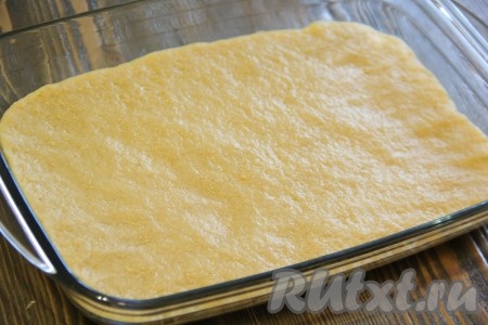 Готовое тесто освободить от пищевой плёнки и выложить на дно жаропрочной формы. Равномерно распределить тесто по дну формы и слегка утрамбовать.