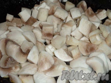 Шампиньоны почистить, помыть и нарезать кубиками. На небольшом количестве растительного масла обжарить грибы до полного испарения жидкости, в течение 10-15 минут, периодически помешивая.  
