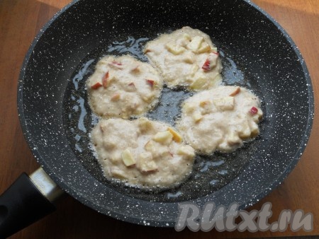 В сковороде разогреть растительное масло. Выкладывать тесто в сковороду ложкой, чуть придавливая и формируя оладьи с яблоками округлой формы.