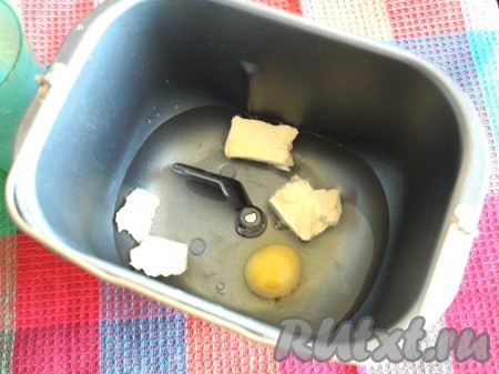 Налить в ведёрко хлебопечки тёплую воду, добавить яйцо и сливочное масло.
