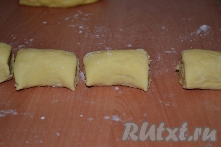 Когда тесто увеличится приблизительно в два раза, обмять и раскатать его в колбаску. Разрезать колбаску на одинаковые кусочки.
