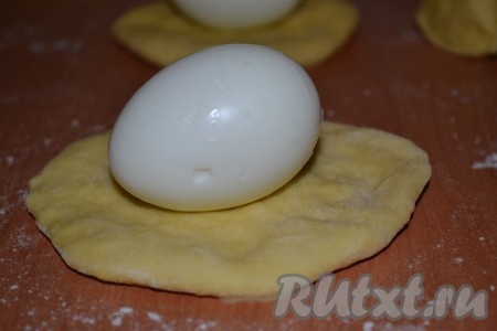 Каждый кусочек раскатать в лепешку, в центр лепешки выложить очищенное вареное яйцо (можно взять перепелиные, но тогда лепешки делайте меньшего размера).

