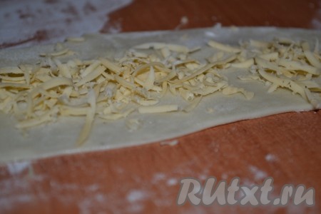 Когда тесто увеличится в два раза, разделить его на равные части. Каждую часть теста раскатать в пласт и посыпать натертым сыром.

