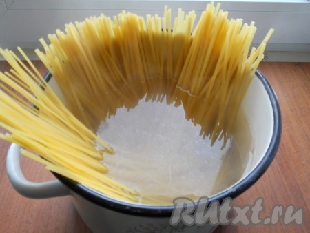 В кипящую подсоленную воду выложить спагетти и отварить до готовности, в соответствии с инструкцией на упаковке. Готовые спагетти откинуть на дуршлаг, воду слить. Спагетти переложить в кастрюлю, добавить сливочное масло и перемешать.
